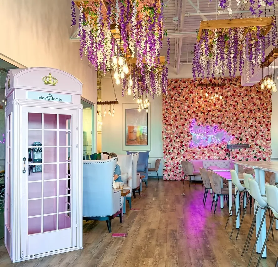 Inside a Raining Berries café with a flower wall and pink phone booth
